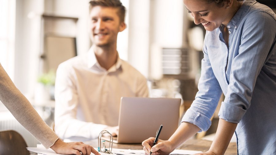 Професійна фінансова експертиза Люди працюють разом за столом та підписують документи.